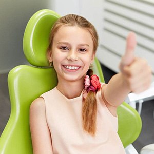 Child smiling while sitting in dentist's treatment chair
