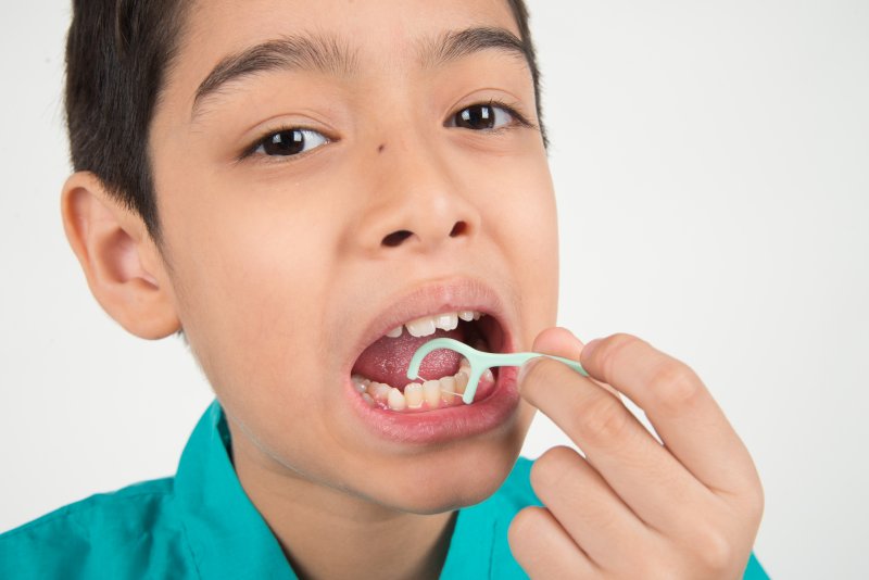 young boy flossing his teeth